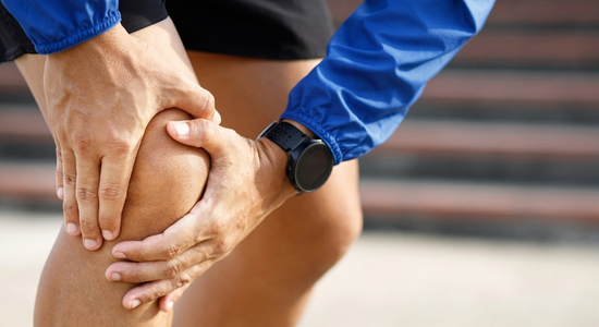 Ein Sportler hält sich sein rechtes Knie.